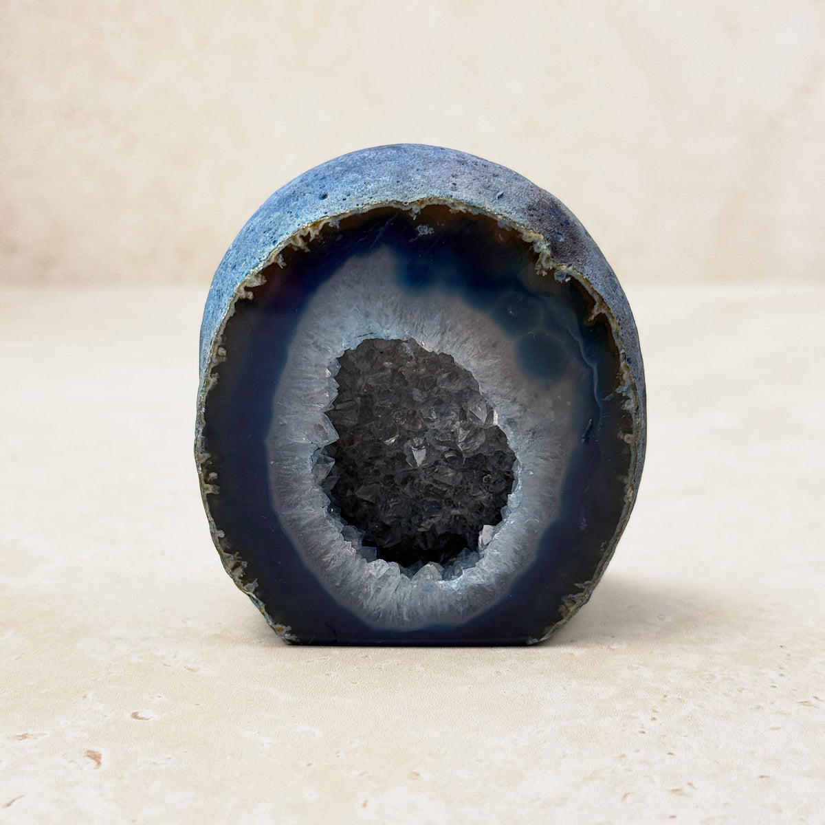 Dyed blue agate crystal geode 7cm, blue bands around a dark crystal hollow, front view — Eternal Spirit