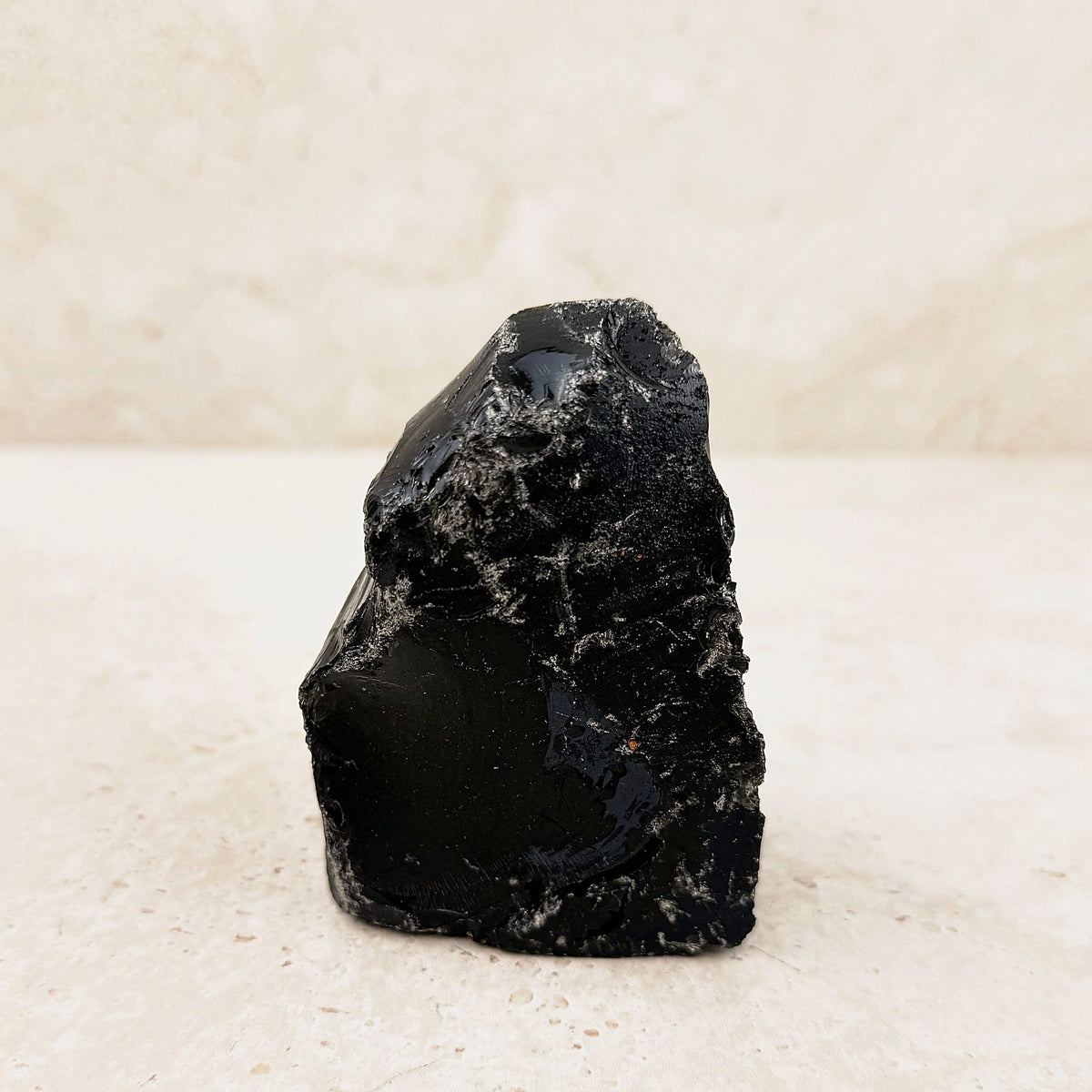 Flecked black obsidian rough 10cm, glassy black faces, angled side view — Eternal Spirit