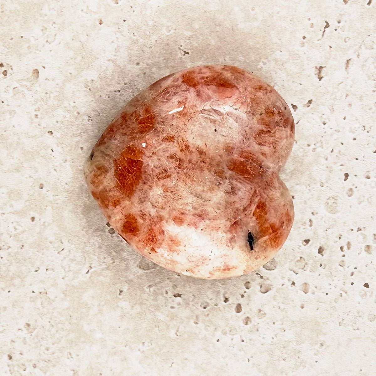 Sunstone crystal heart 5cm, orange flecks across a polished face, angled view — Eternal Spirit