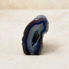 Dyed blue agate crystal geode 6cm, blue and brown bands around a narrow hollow, front view — Eternal Spirit