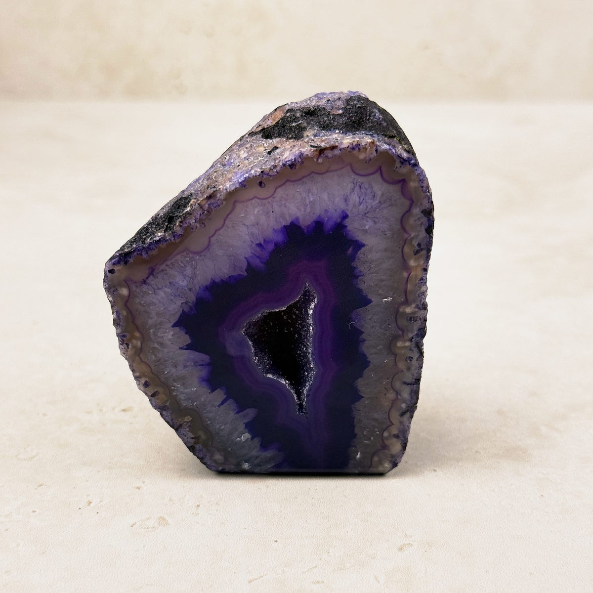 Dyed purple agate crystal geode 6.5cm, purple bands around a dark crystal hollow, front view — Eternal Spirit