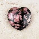 Marbled rhodonite crystal heart 5cm, bold black lines across deep pink, viewed from above — Eternal Spirit