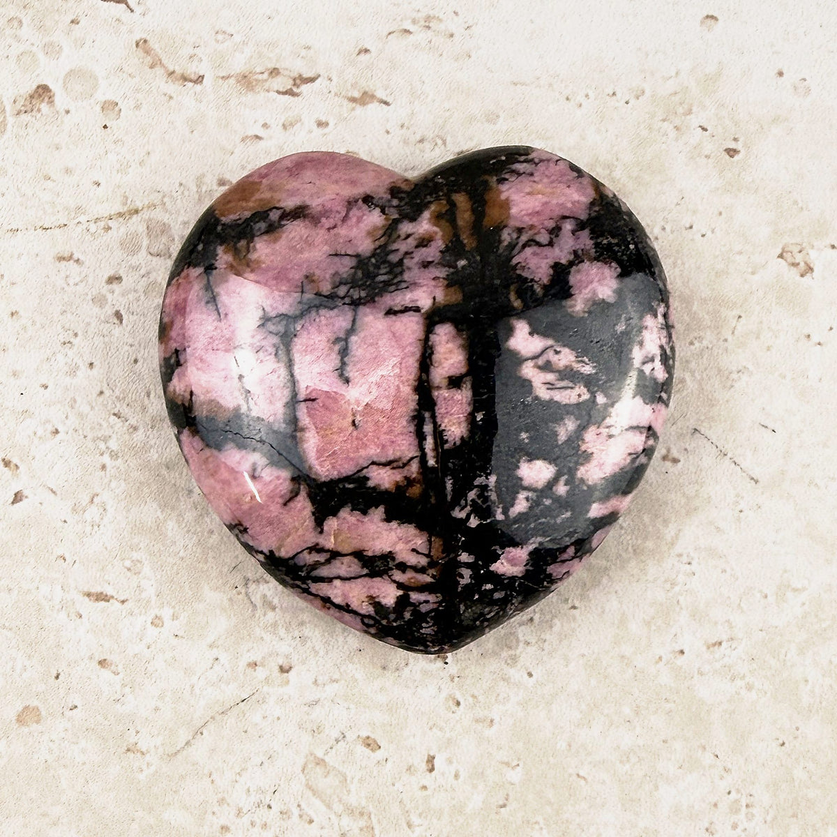 Marbled rhodonite crystal heart 5cm, bold black lines across deep pink, viewed from above — Eternal Spirit