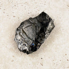 Silvery elite shungite rough crystal 7cm, silvery flashes across its faces, angled view — Eternal Spirit